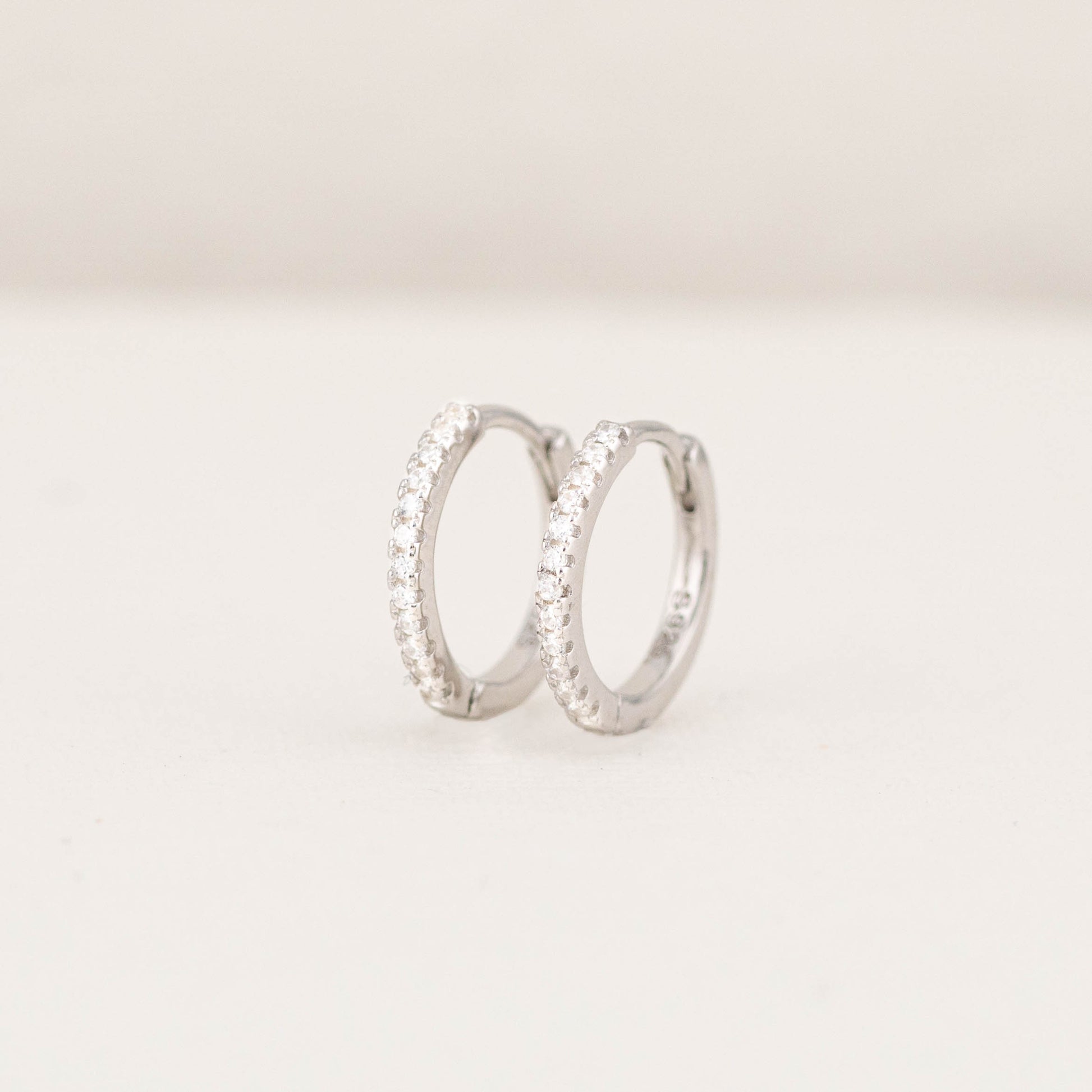 Front view of thin diamond silver hoop earrings, showing the small sparkling stones. 