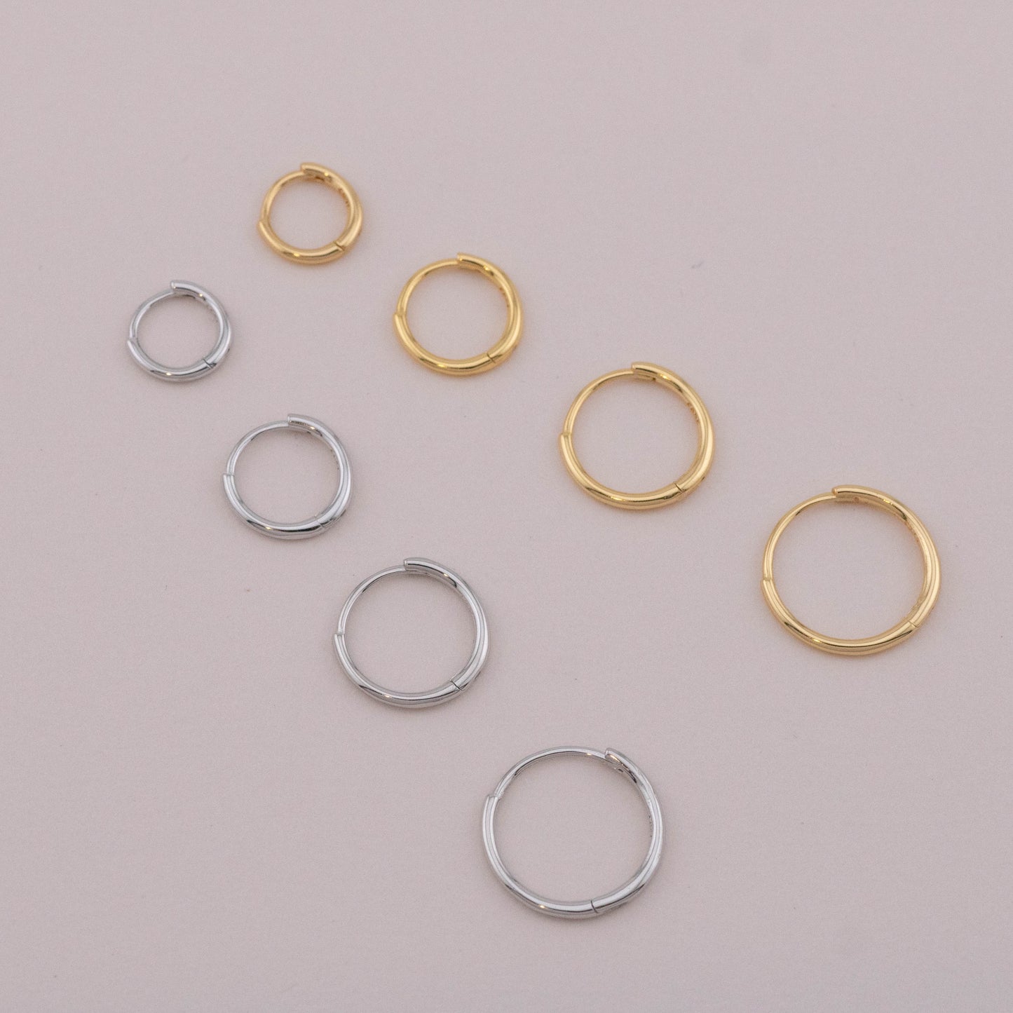 Gold and silver stackable huggies laid down, top view, showing different sizes for everyday wear.