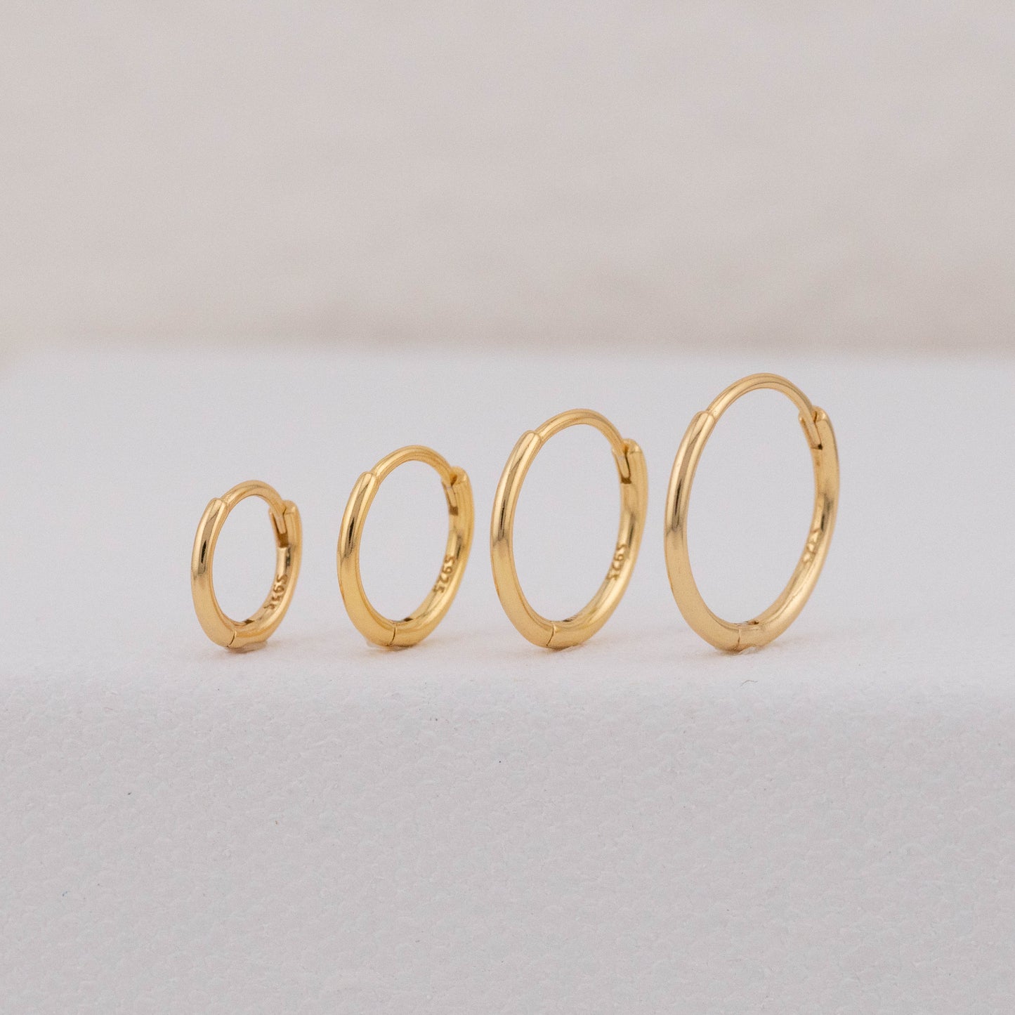 gold hoops in different sizes are displayed upright, showing stackable earring sets for 2 holes