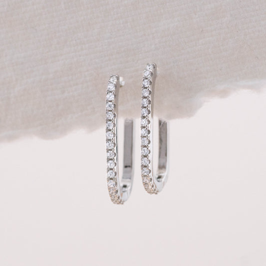 Square silver earrings with pave stones, shown hanging to display how they look when worn.