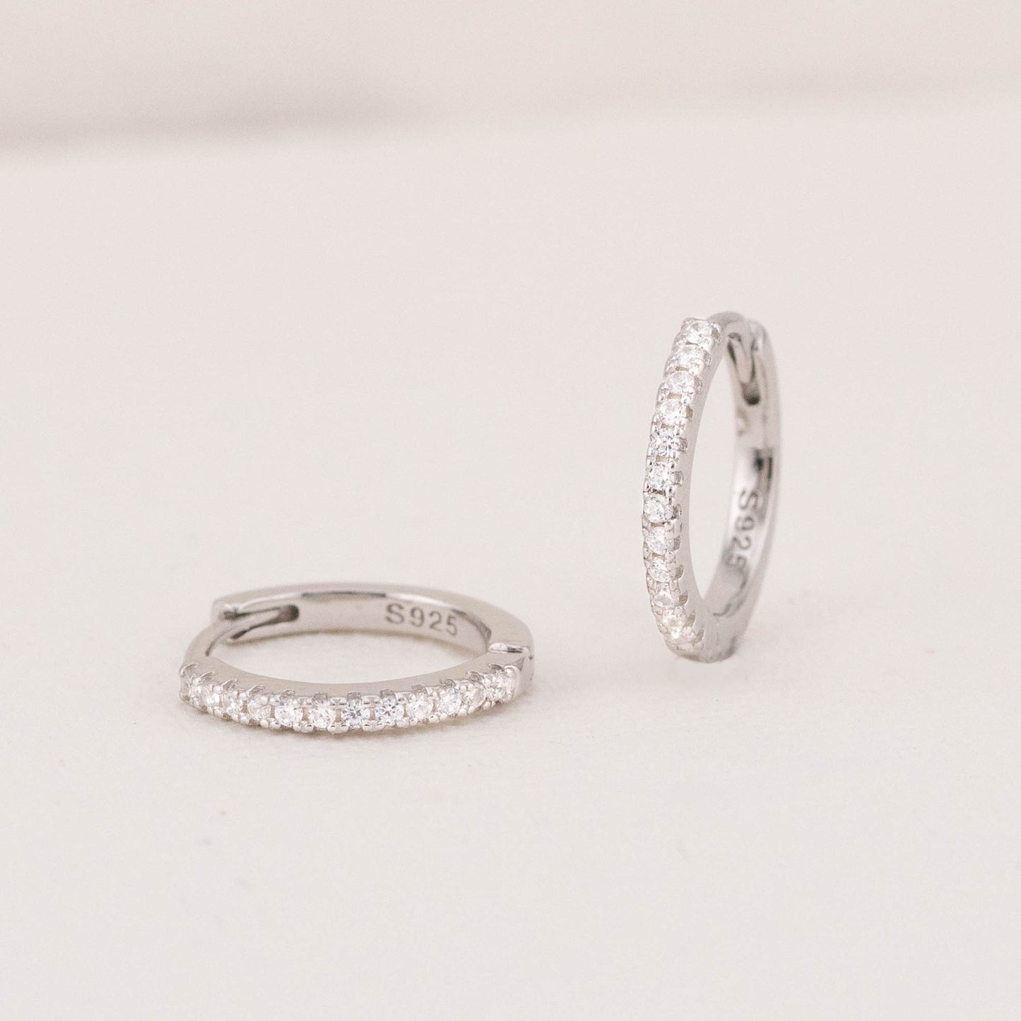 Silver mini diamond hoops, standing and lying down, highlighting their shimmering pave design.