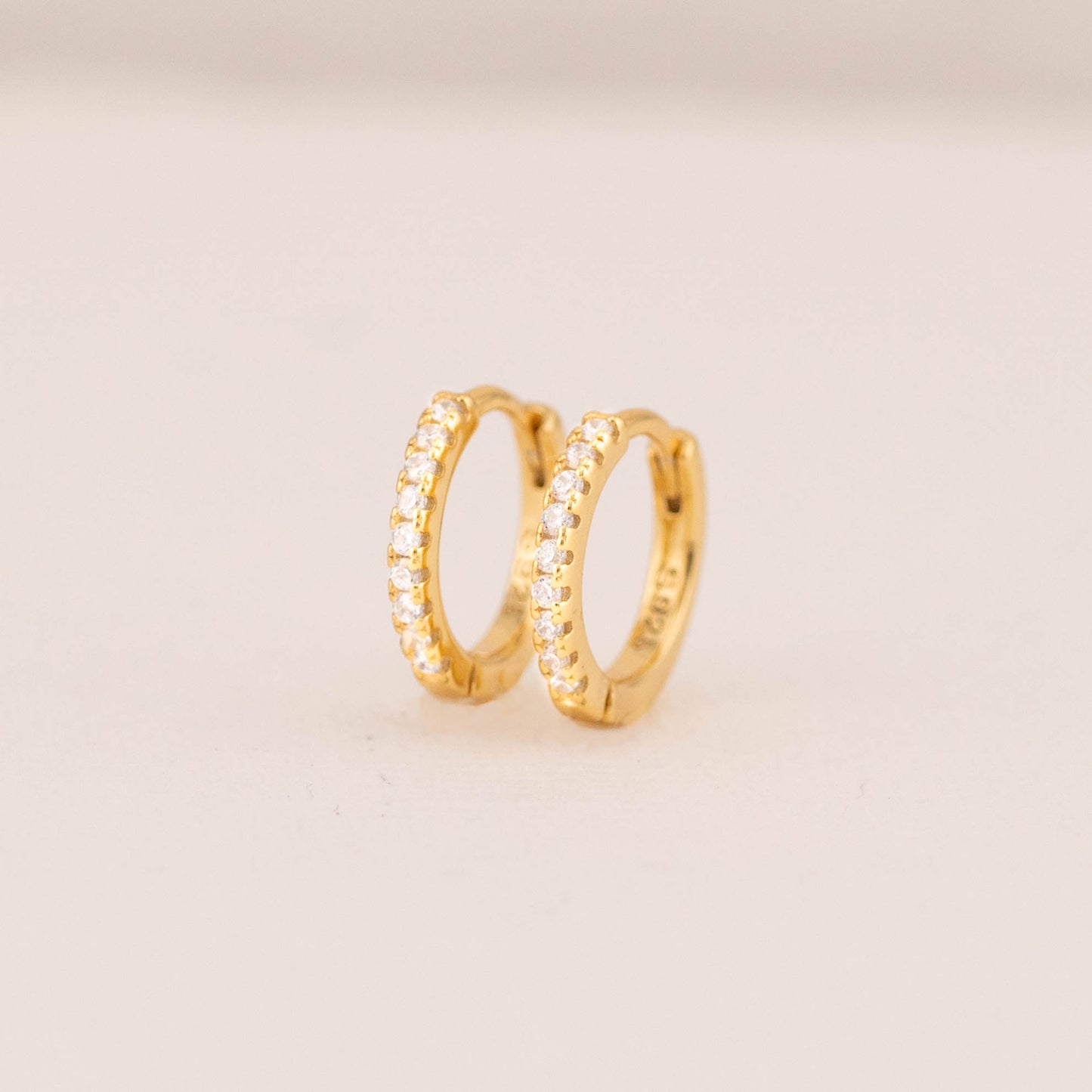 Detailed view of gold hoop earrings with sparkling cubic zirconia pave stones.